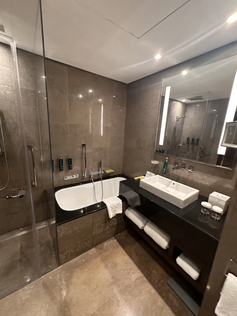 Wide shot of bathroom within a twin room at the Hilton Riyadh, showing the basin, shower and bath