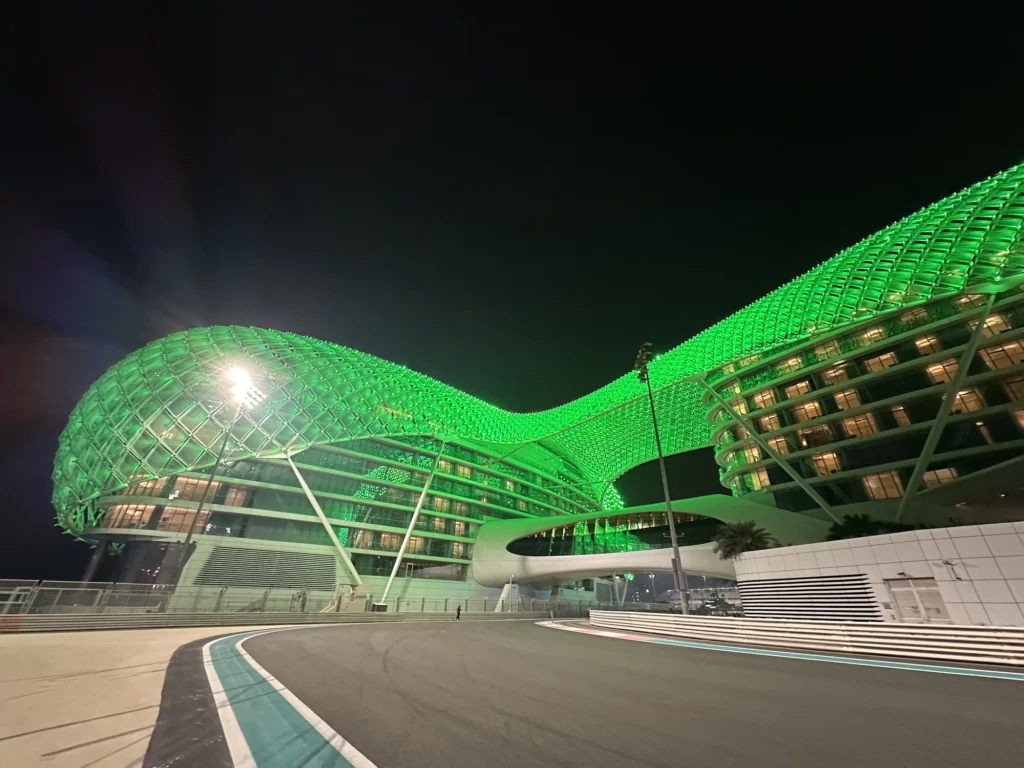 External photograph of the hotel from the F1 track, taken at night and the hotel glowing green