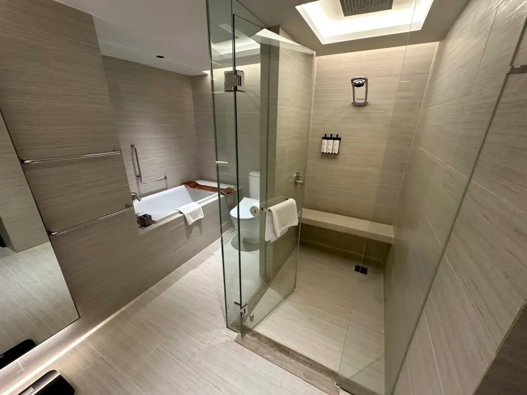 The big shower complete with a seat and the bath and toilet in the background The big shower complete with a seat and the bath and toilet in the background
