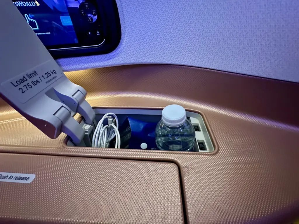 A small storage space to the side of the seat with a water bottle A small storage space to the side of the seat with a water bottle