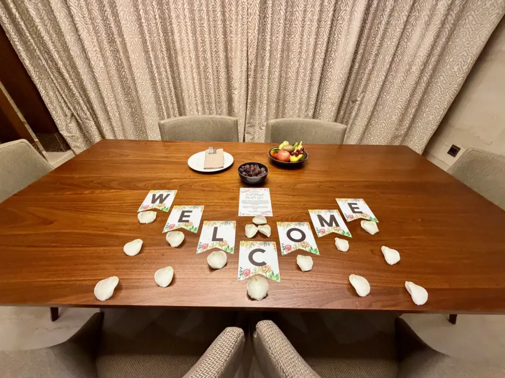 A photograph of the dining table inside a villa, with "Welcome" spelled out on the surface. 