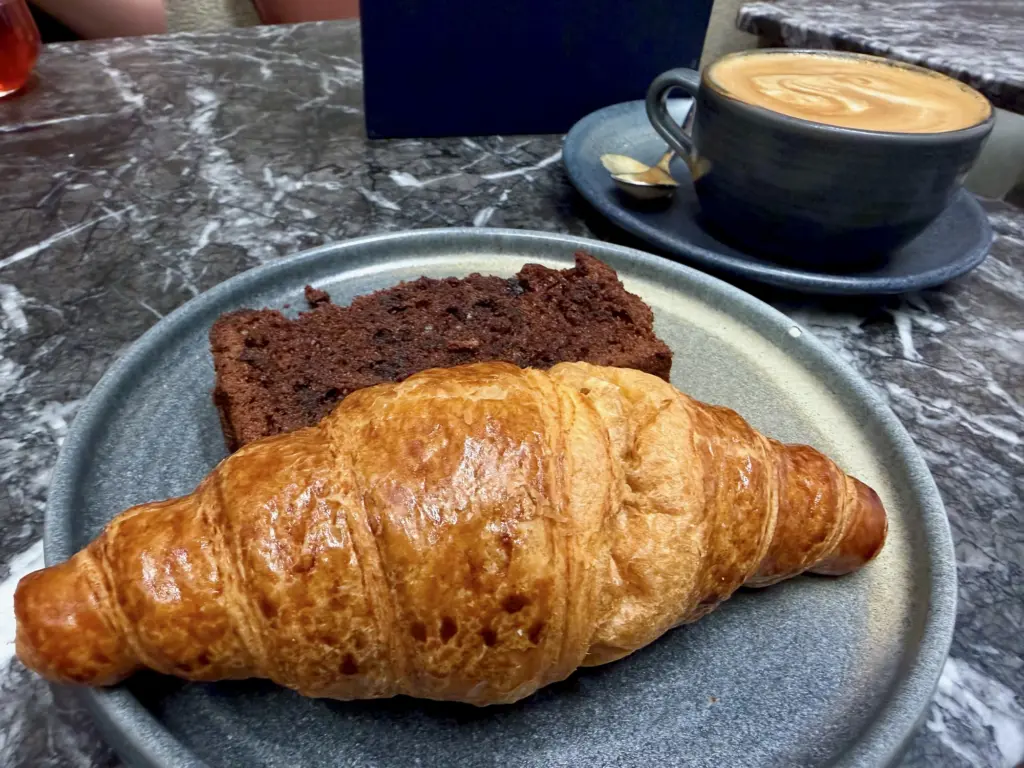 A photograph of a croissant and double chocolate loaf cake