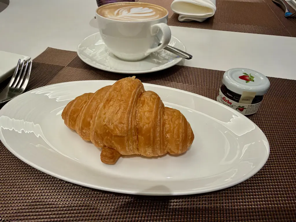 A croissant and my dark roast coffee A photograph showing a croissant and coffee in the dining area of the Qatar Bangkok lounge